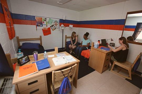 Students in a Keystone College dorm room sitting on a bed.